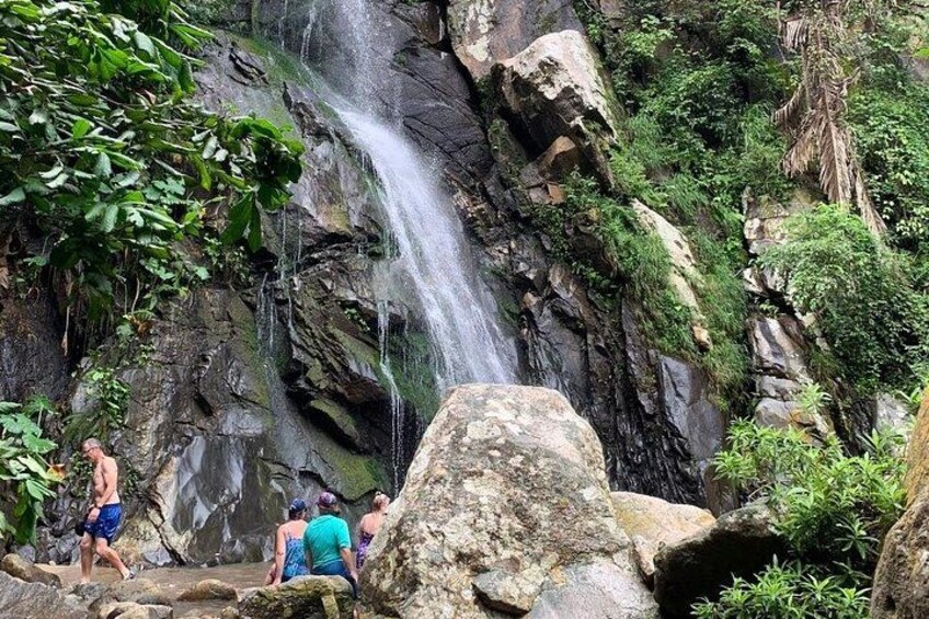 A waterfall cascading down a rocky cliff surrounded by lush greenery. 2