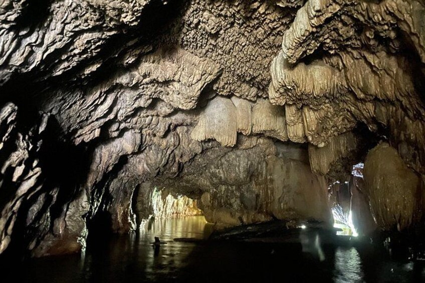 Een grot met stalactieten en -stalagmieten, een waterstroom en een persoon die in het water staat. 2