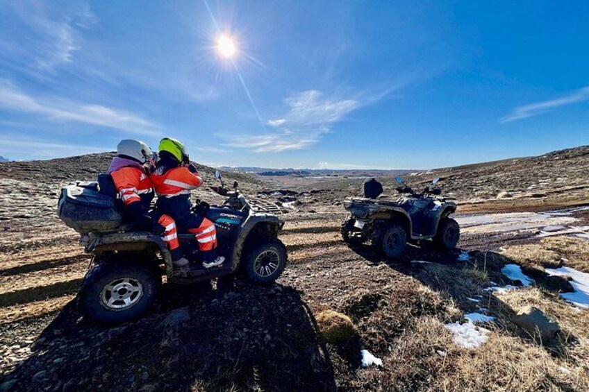 Two people on ATVs in a rugged, open landscape with a clear sky. 4
