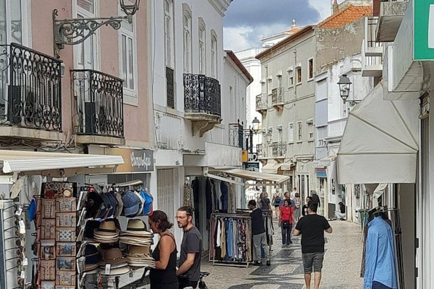 A narrow street with shops and people walking. 3