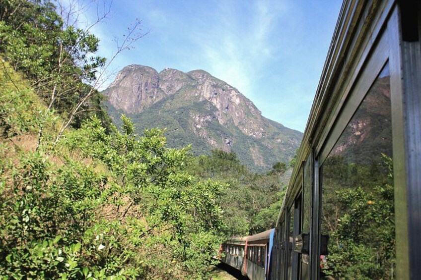 A train traveling through a mountainous landscape with dense greenery and rocky cliffs. 2