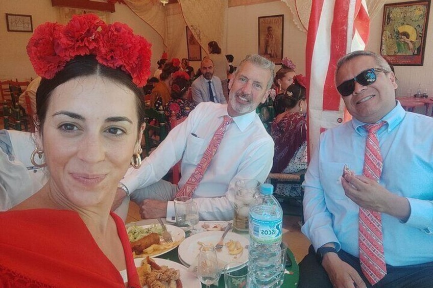 People sitting at a table with food and drinks, in a room with red and white decorations. 1