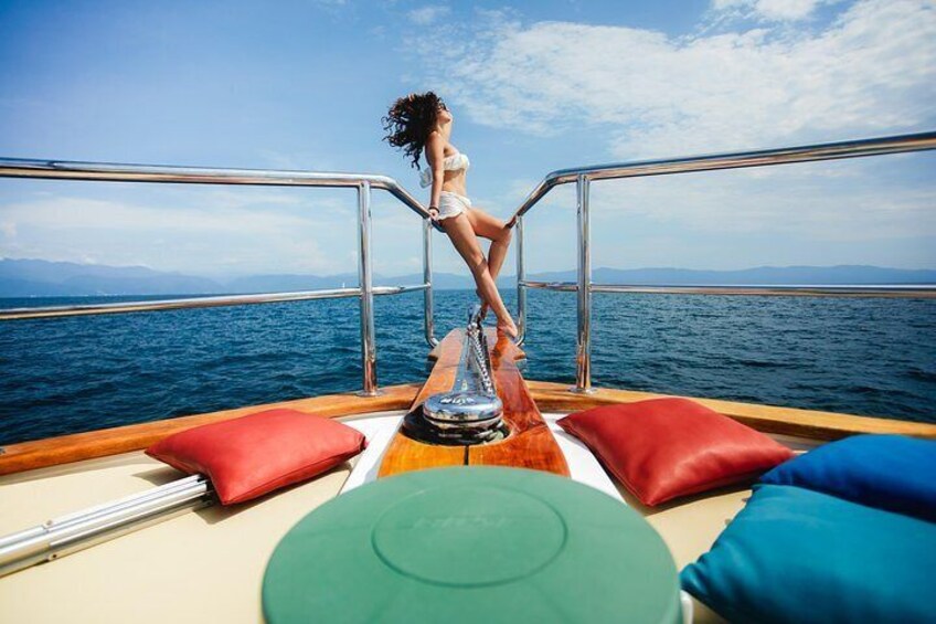 A person standing on a boat deck with a view of the ocean and mountains in the distance. 4