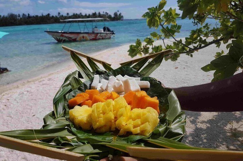 Une assiette de nourriture sur une plage, avec un bateau en arrière-plan. 5