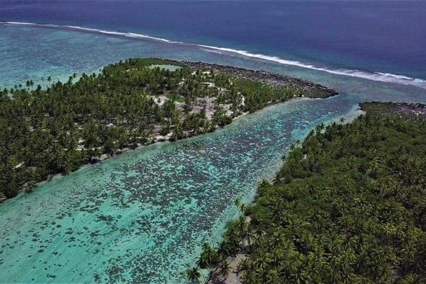 An aerial view of a tropical island with clear turquoise waters, dense green vegetation, and a narrow passage between the landmasses. 4