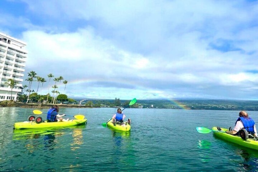 Tres personas haciendo kayak en aguas tranquilas, con un arcoíris al fondo. 4