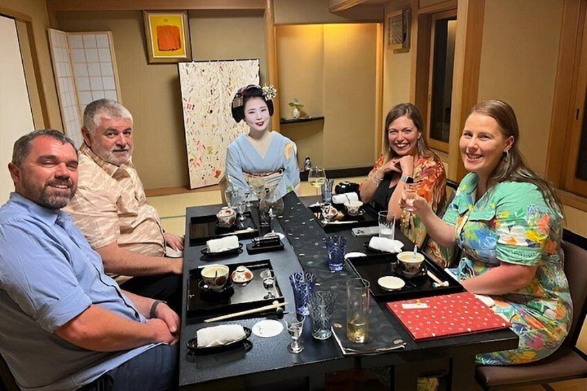 A group of people seated around a table with various dishes and drinks. 2