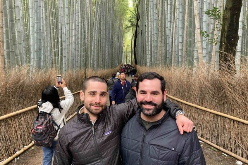 Twee personen staan op een pad door een bamboebos, met een touwbarrière. 5