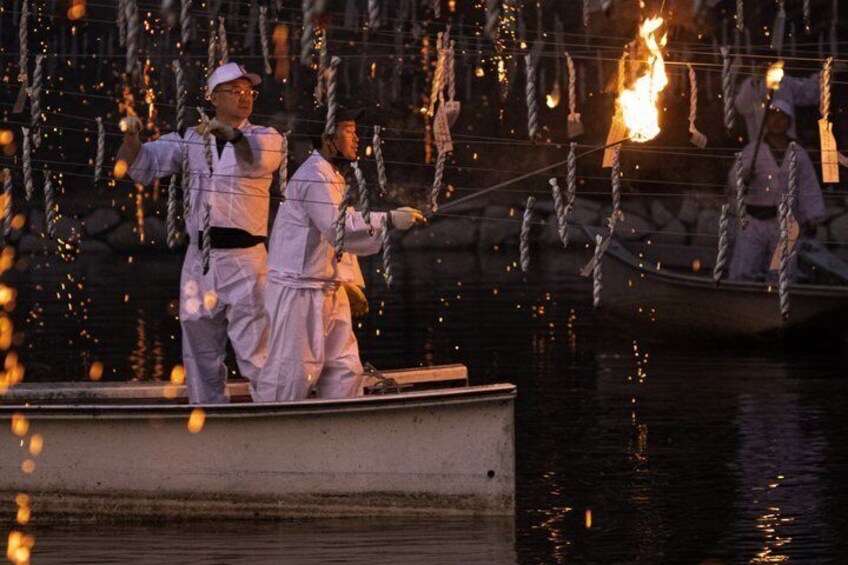People in white uniforms performing with torches on a boat. 4