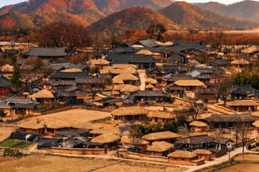 A traditional village with thatched-roof houses, surrounded by mountains. 2
