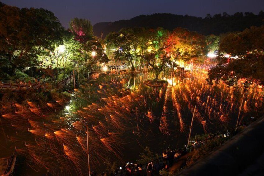 A nighttime park with illuminated trees and a reflective water surface. 3