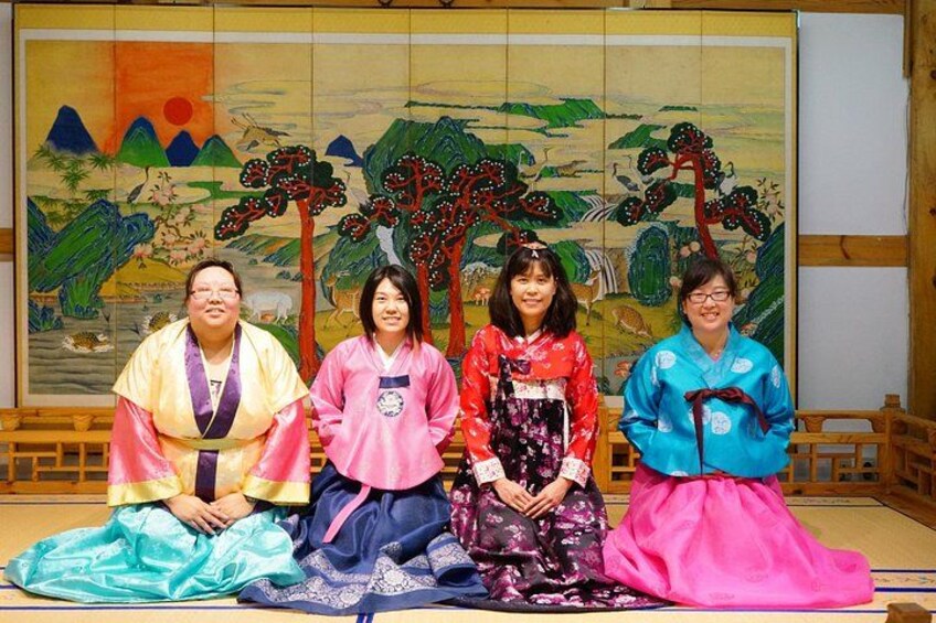 Vier personen in traditionele kledij zitten op tatami-matten voor een culturele achtergrond. 3