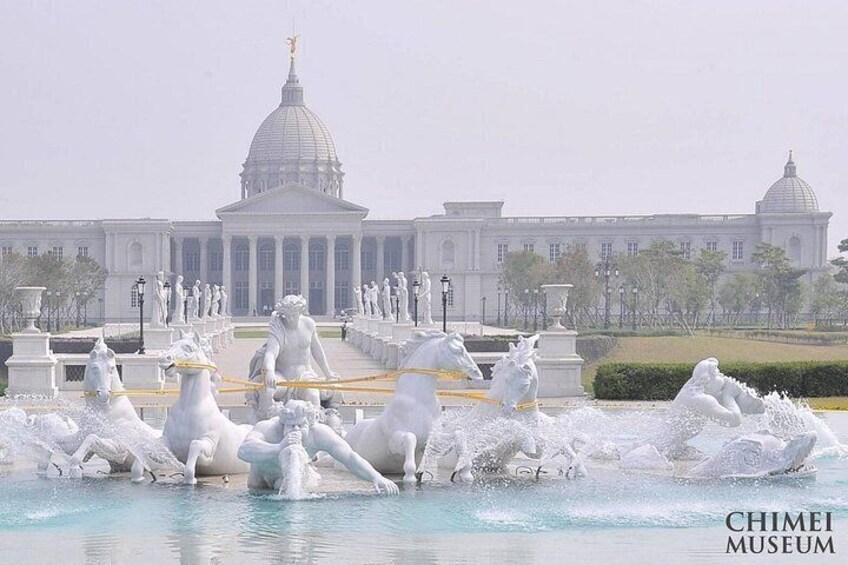 A fountain with white horse statues in front of a large white building with domes. 3