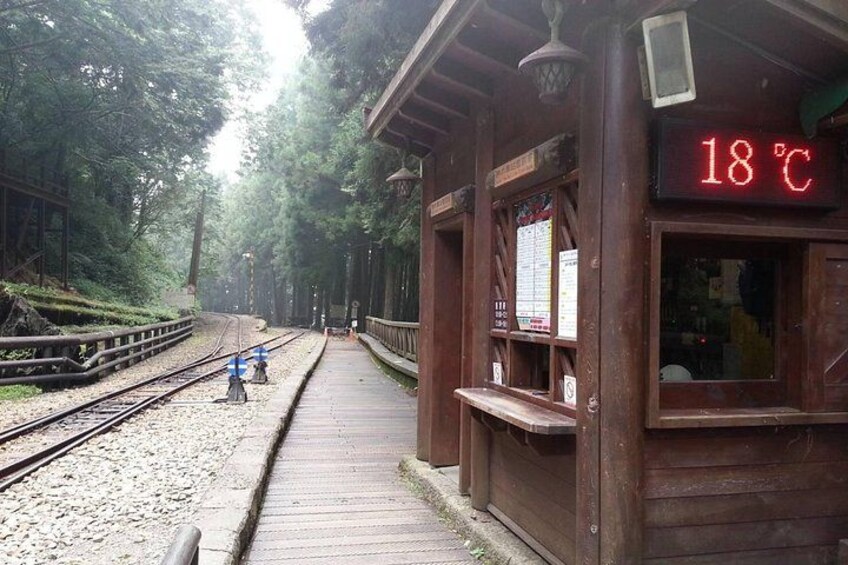 A wooden train station platform with a temperature sign reading 18°C. 1