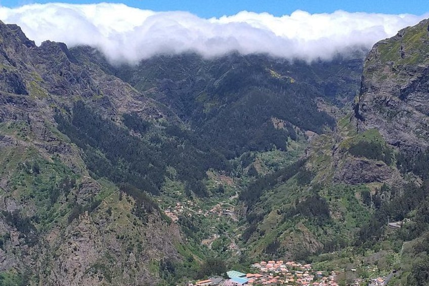 A mountainous landscape with a valley, dense forests, and a small settlement. 1