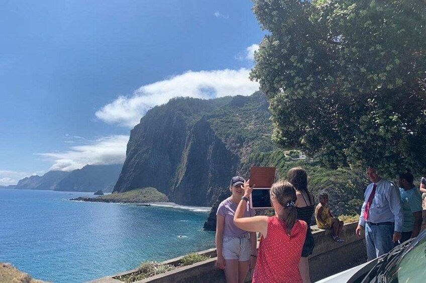 A coastal landscape with cliffs, a clear sky, and a group of people near the water. 4