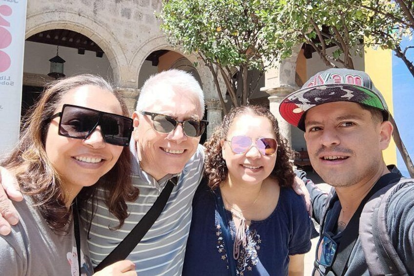 Four people posing in front of a building with arches. 3