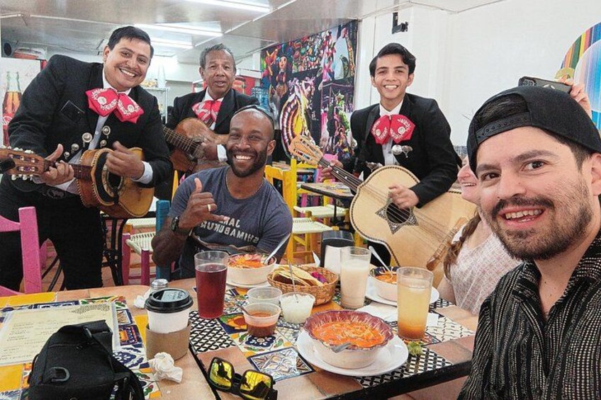A group of people around a table with food, drinks, and musical instruments. 4