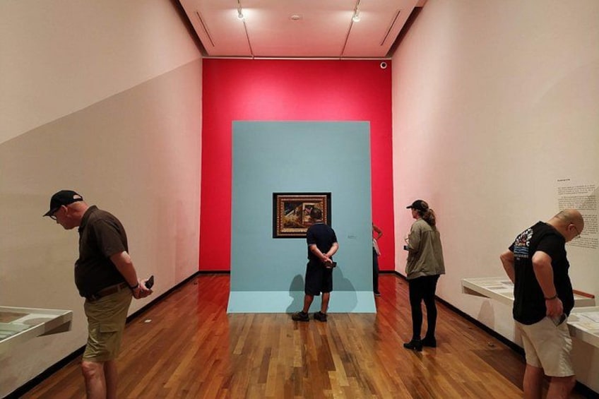 An art gallery with wooden floors and red walls. 2