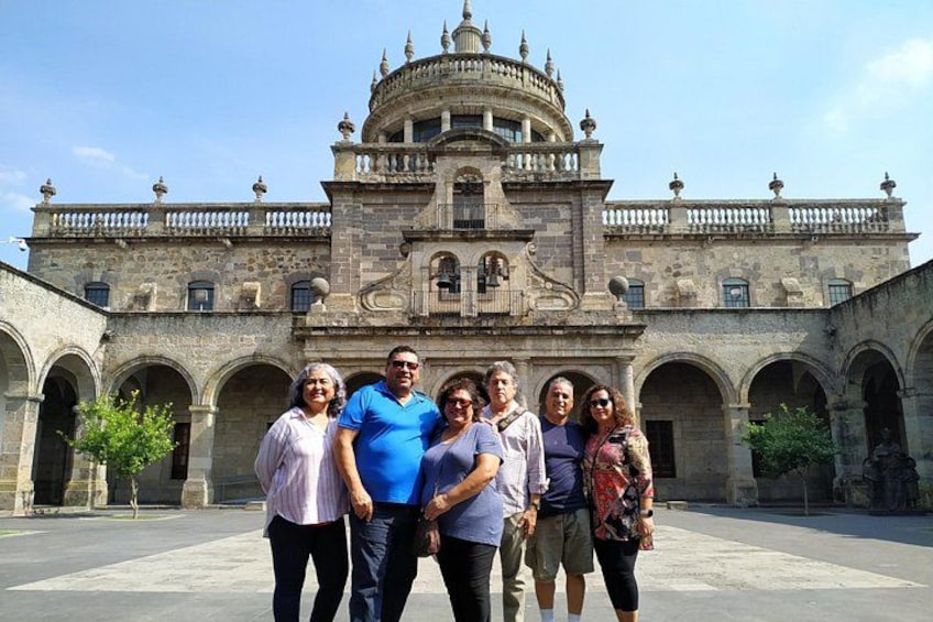 A group of people standing in front of a historic building with arches and a dome. 1