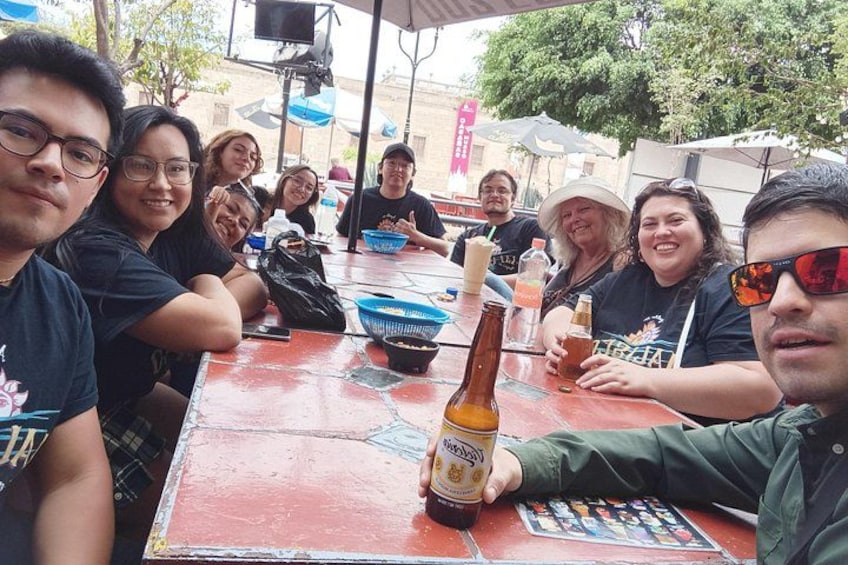 A group of people sitting around a table with drinks and a bottle of beer. 3