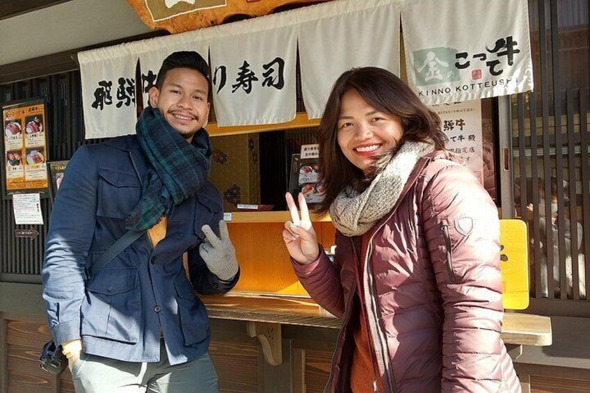 Two people standing in front of a food stall with Japanese signage. 2