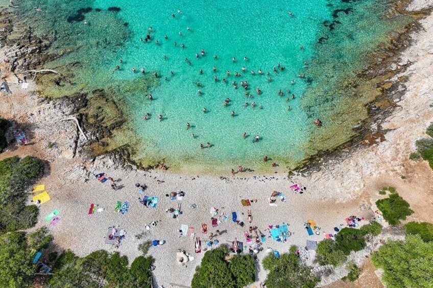 Une vue aérienne d’une plage bondée, où l’on voit des gens se baigner et prendre des bains de soleil. 1