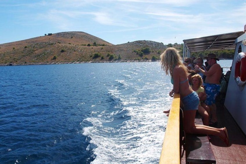 Un barco navegando en un cuerpo de agua, con personas a bordo, un paisaje montañoso al fondo y un cielo despejado. 2