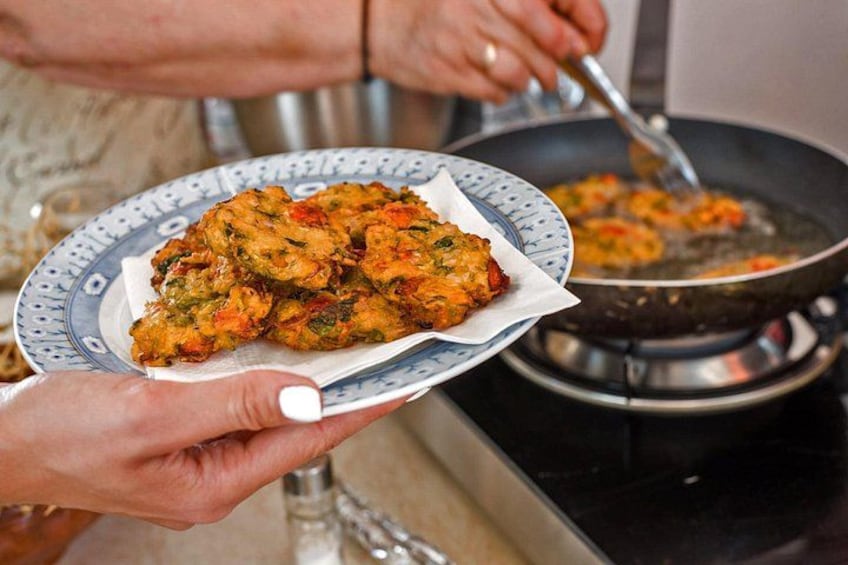 Een persoon houdt een bord eten vast, met een pan op de achtergrond. 1