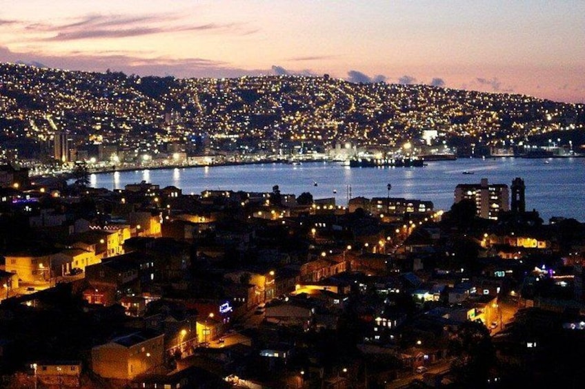 A coastal cityscape at dusk with illuminated buildings and a river. 5