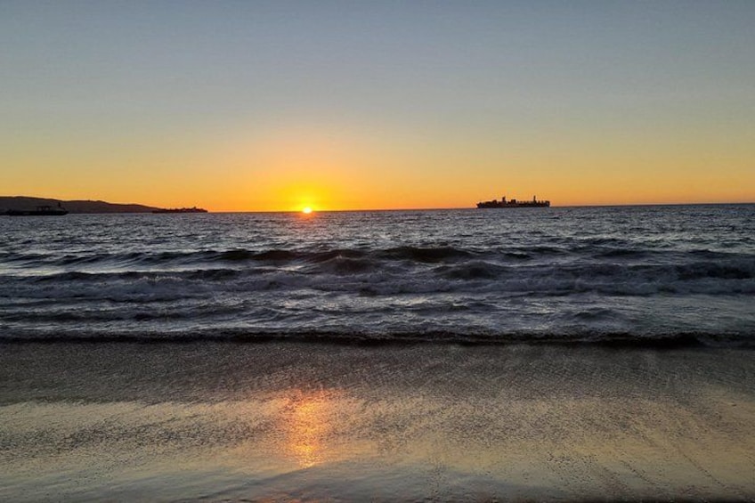 A sunset over the ocean with waves and a distant ship. 4