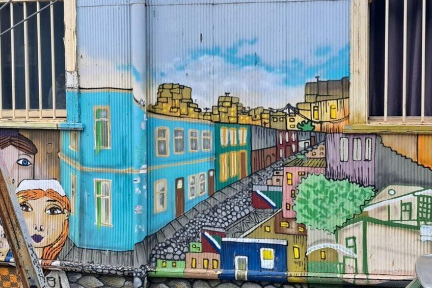 A mural of a cityscape with buildings, a staircase, and a tree. 2