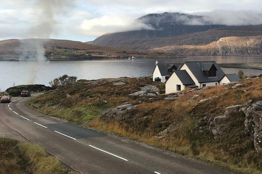 Una carretera serpentea alrededor de un lago con casas y humo elevándose desde el agua. 4