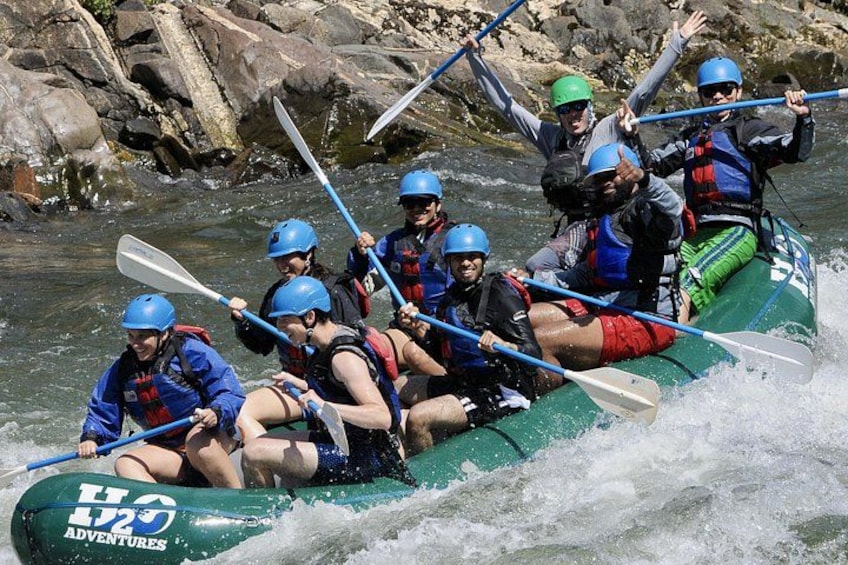 Un groupe de personnes à bord d’un radeau vert naviguant sur une rivière à courant rapide. 2