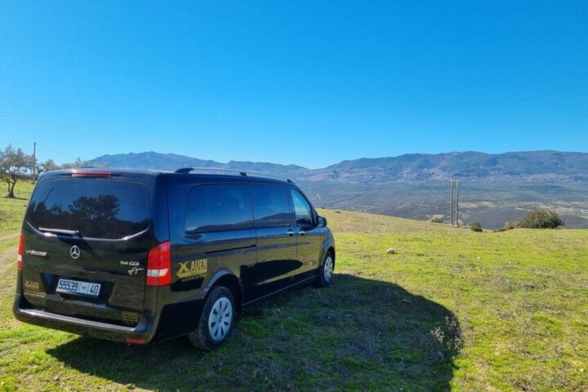 A Mercedes-Benz Sprinter van parked on a grassy field with a mountainous backdrop. 3