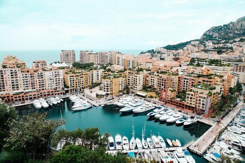 A marina with numerous boats docked, surrounded by residential buildings and a mountainous backdrop. 2