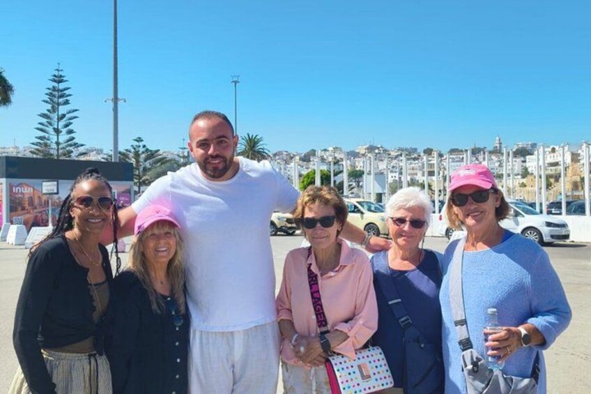 A group of people standing in a parking lot with a clear sky and buildings in the background. 1
