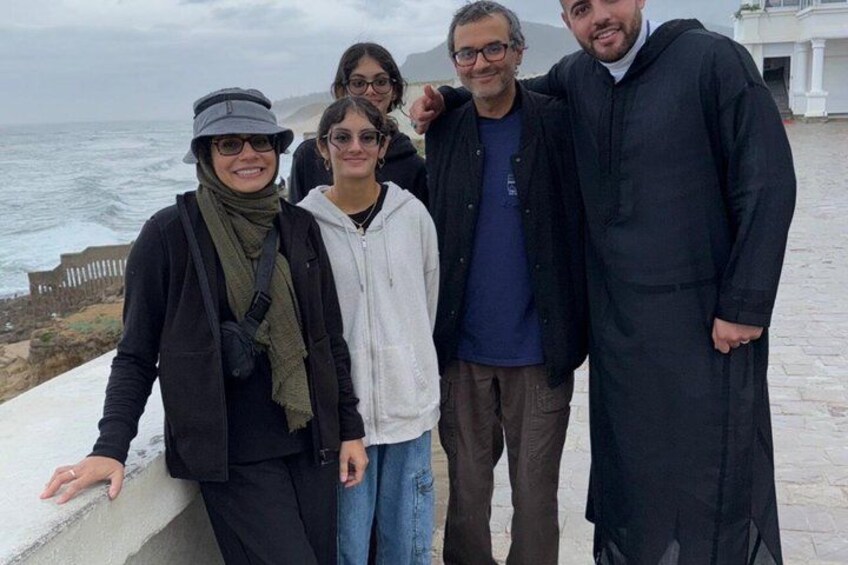 A group of people standing on a stone-paved area with a view of the ocean. 2