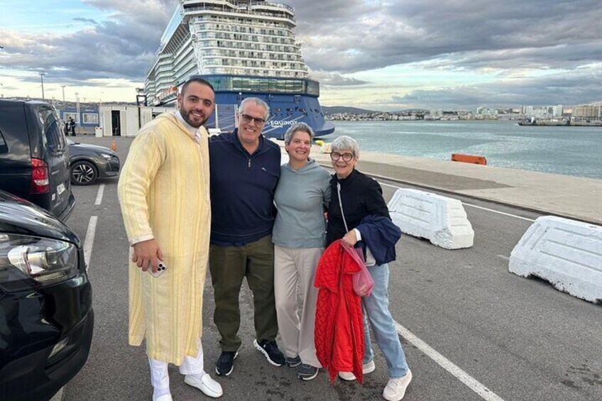 A group of people standing in a parking lot with a cruise ship in the background. 4