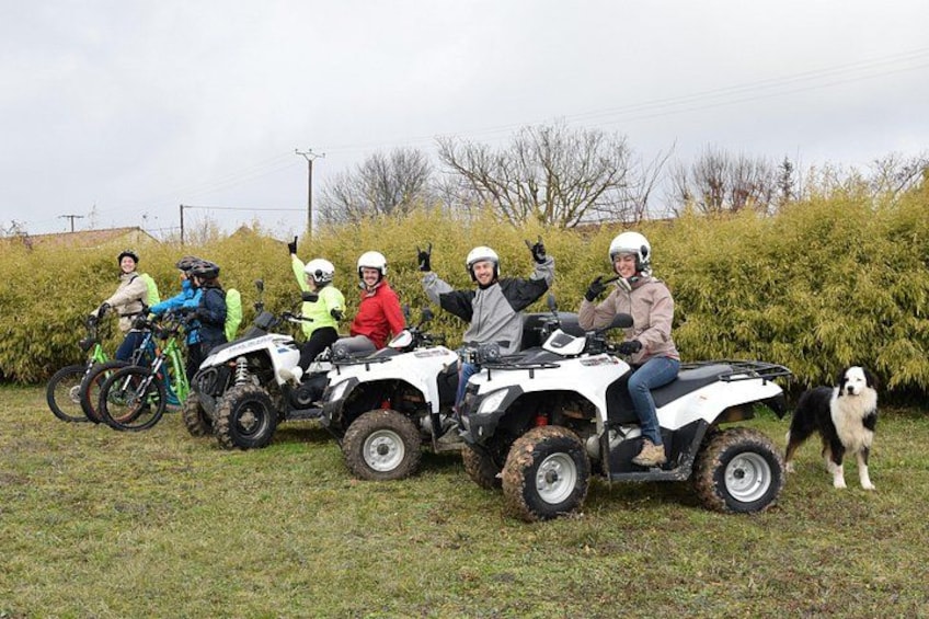 Un groupe de personnes sur des quads et des vélos, se trouvant dans une zone herbeuse, avec des buissons et des arbres en arrière-plan. 2