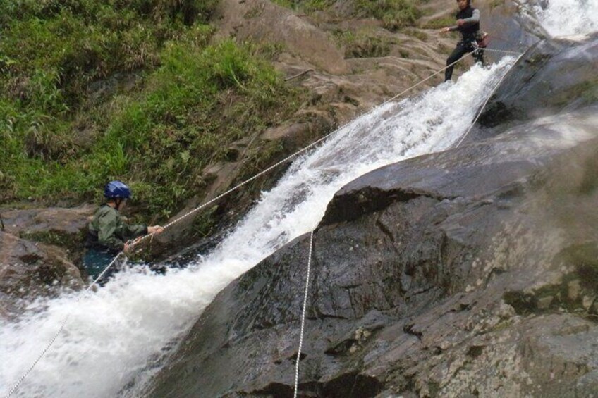Two people rappelling down a rocky waterfall. 1
