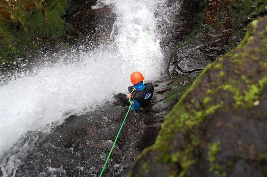 Una persona descendiendo en rappel por una cascada rocosa. 4