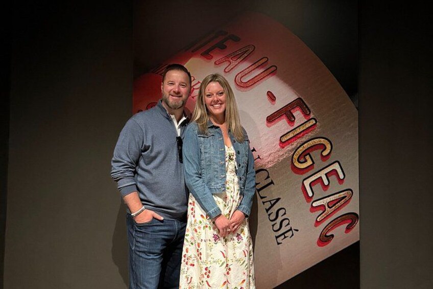 Two people standing in front of a wall with text and graphics. 2