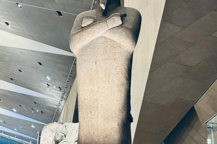 Eine große Steinstatue in einem Innenraum mit moderner Decke und Fliesenboden. 3