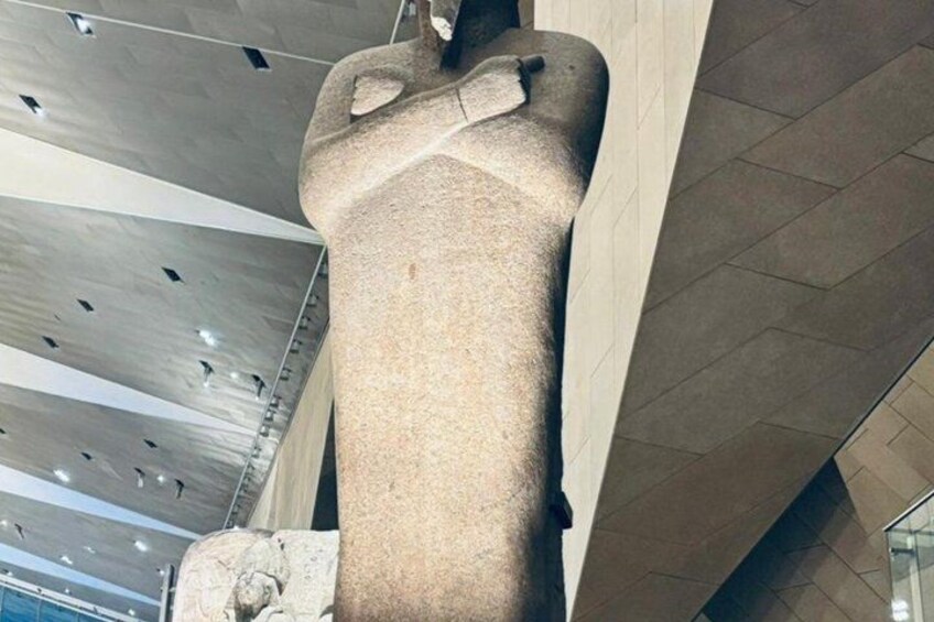 En stor stenskulptur placerad i en inomhusmiljö med högt i tak och modern arkitektur. 3