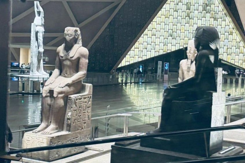 A museum interior with ancient Egyptian statues and a patterned wall. 3