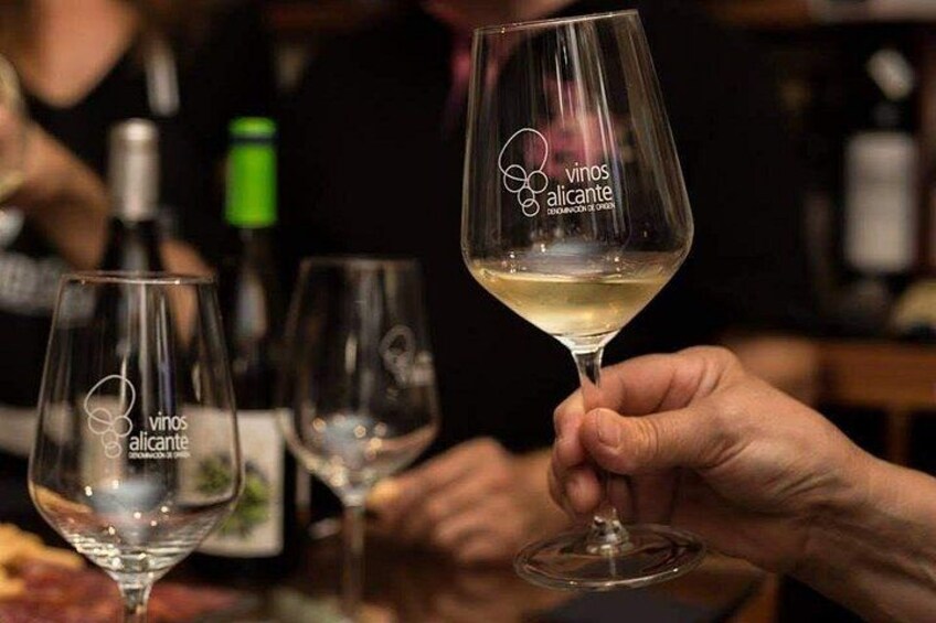Une personne tenant un verre à vin orné du logo « vinos alicante ». 4
