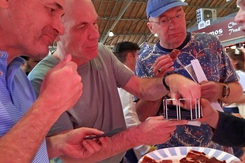 Personas en un puesto de comida, comiendo y sosteniendo recipientes con comida. 3