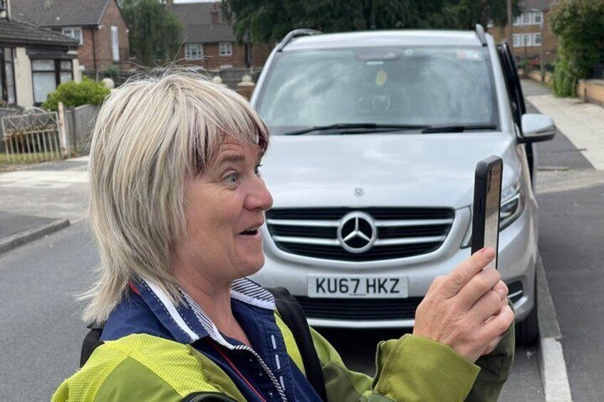 A person taking a photo with a smartphone, a silver Mercedes-Benz car, and a residential street. 4