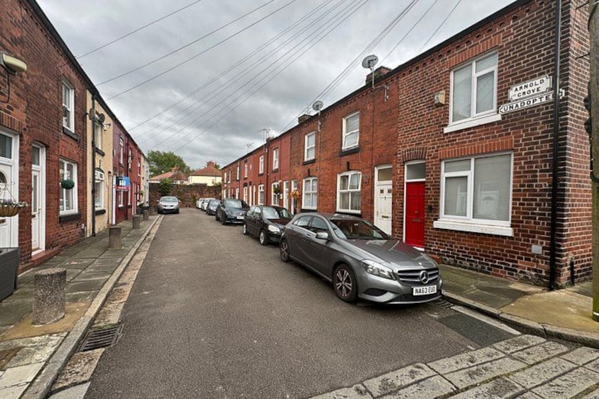 A residential street with parked cars, brick houses, and a red door. 2